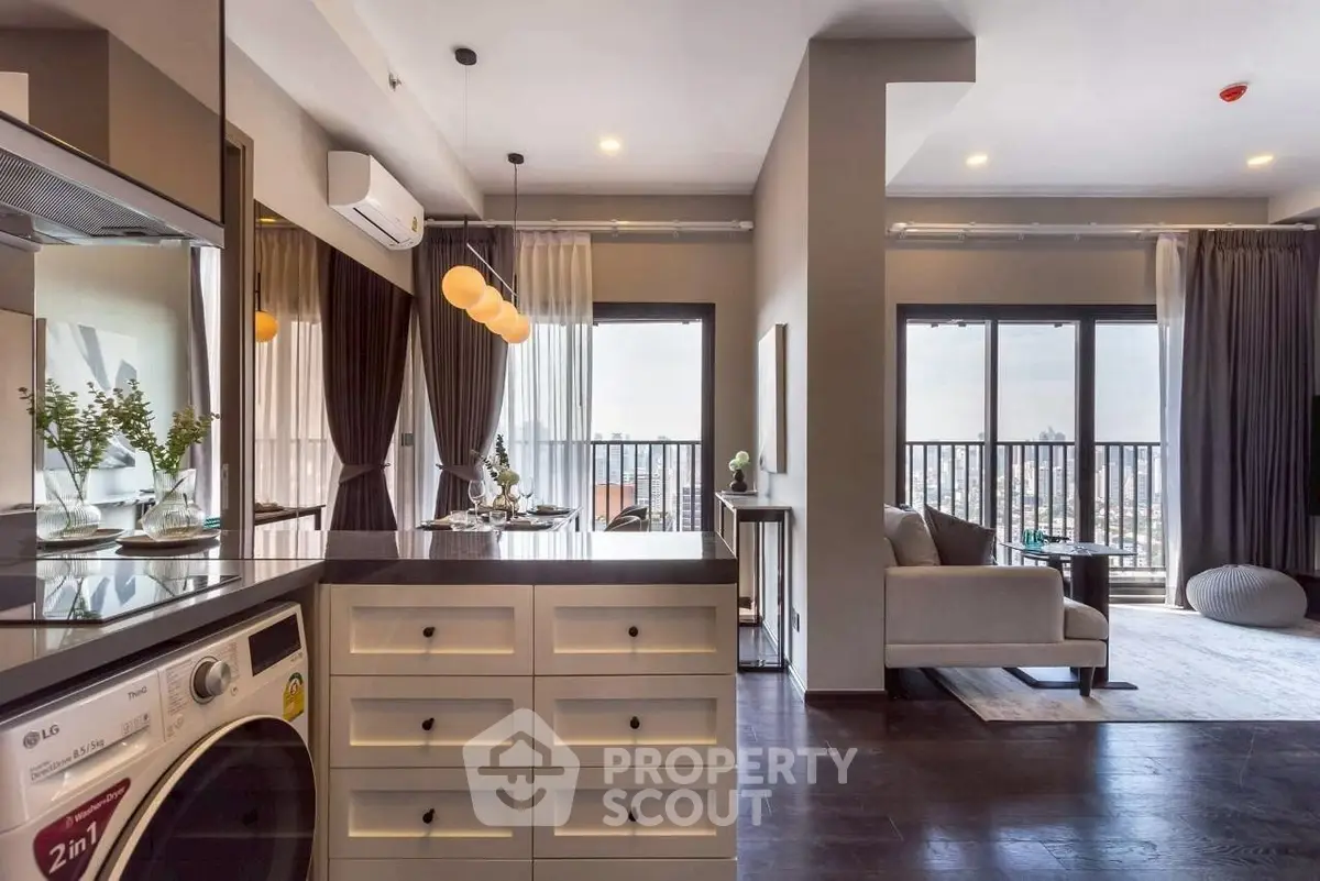 Modern open-plan living room with city view and stylish kitchen featuring a washing machine.