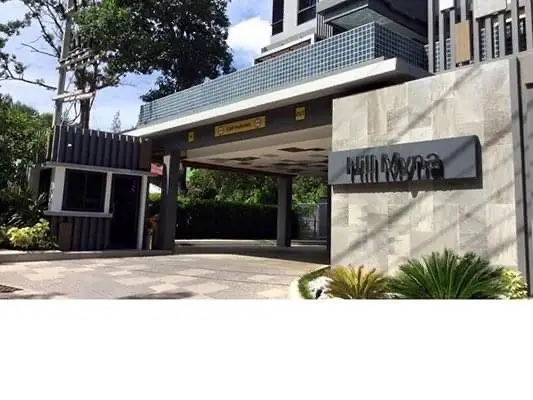 Modern building entrance with stylish design and lush greenery.