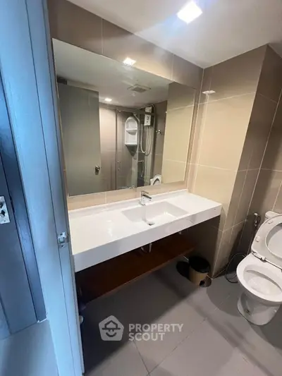 Modern bathroom with sleek fixtures and large mirror in contemporary apartment.
