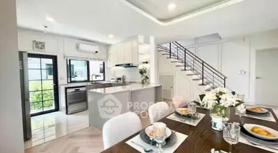 Modern open-plan kitchen and dining area with elegant staircase and stylish decor.