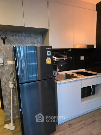 Modern kitchen with sleek black fridge and compact design in stylish apartment.