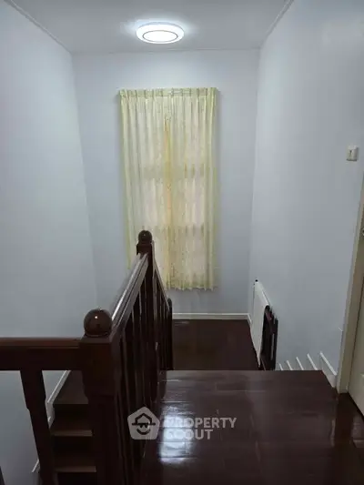 Charming staircase with wooden railing and soft lighting in a cozy home interior.