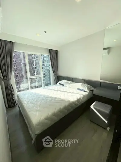 Modern bedroom with large window and city view in high-rise apartment