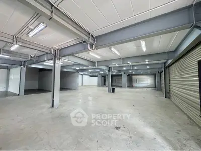 Spacious industrial-style open space with high ceilings and ample lighting, perfect for commercial use.