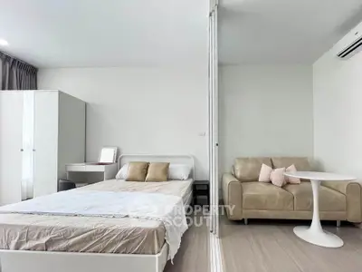 Modern studio apartment with cozy bed and stylish sofa, perfect for urban living.