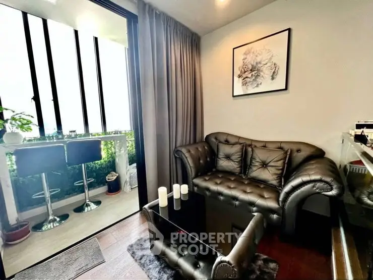 Stylish living room with leather sofa and glass coffee table, opening to a lush balcony view.