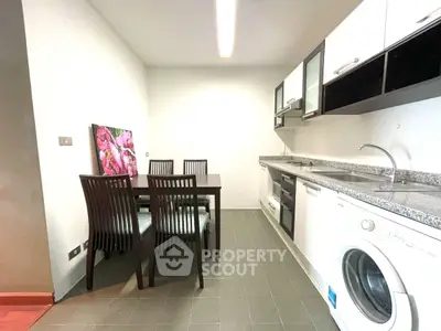 Modern kitchen with dining area, featuring sleek appliances and stylish decor.