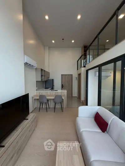 Modern living room with high ceiling and open kitchen layout in a stylish apartment.