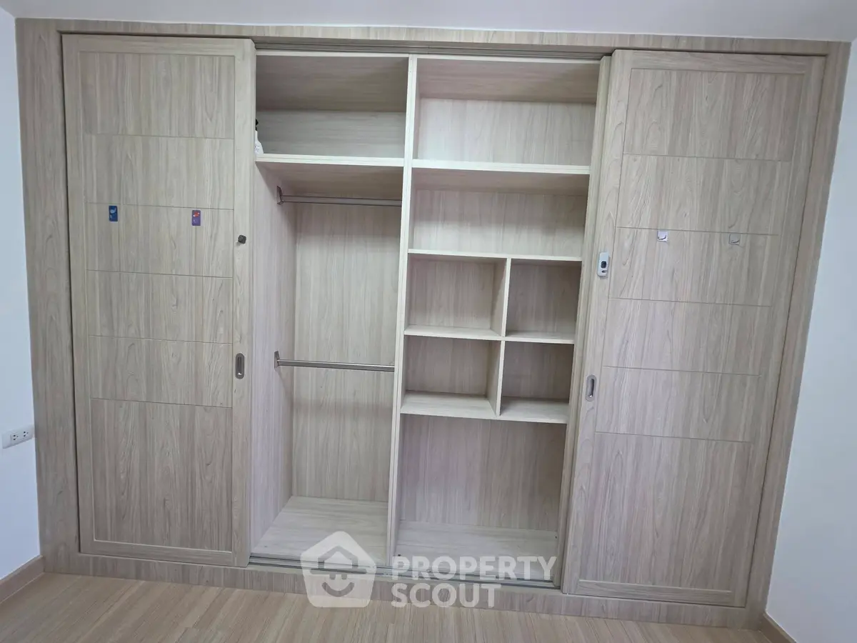 Spacious built-in wooden wardrobe with sliding doors and ample storage space.
