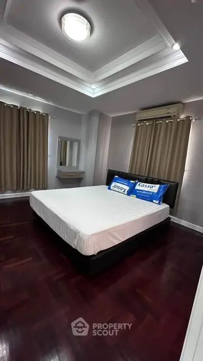 Spacious bedroom with elegant wooden flooring and modern lighting, perfect for relaxation.