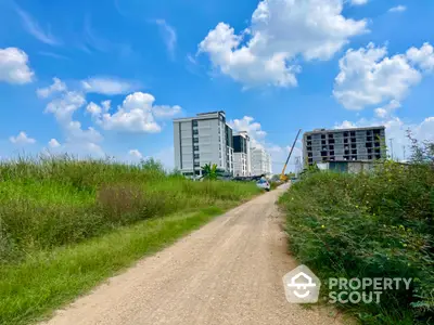 Emerging residential area with modern apartment buildings under a clear blue sky, surrounded by lush greenery, offering a blend of urban living and nature's tranquility.