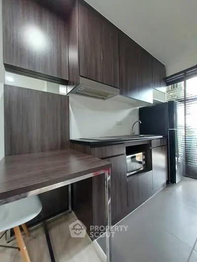 Modern kitchen with sleek dark wood cabinets and built-in appliances in a contemporary apartment.