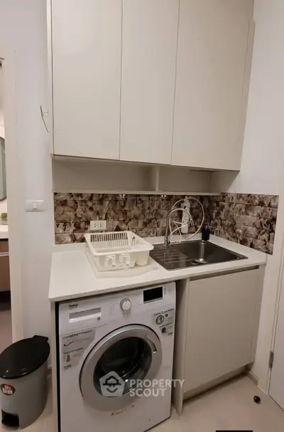 Modern laundry area with washing machine and sink in compact space