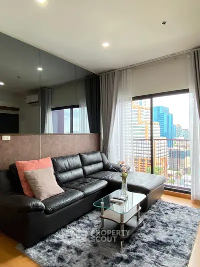 Modern living room with city view, featuring black leather sofa and glass coffee table.
