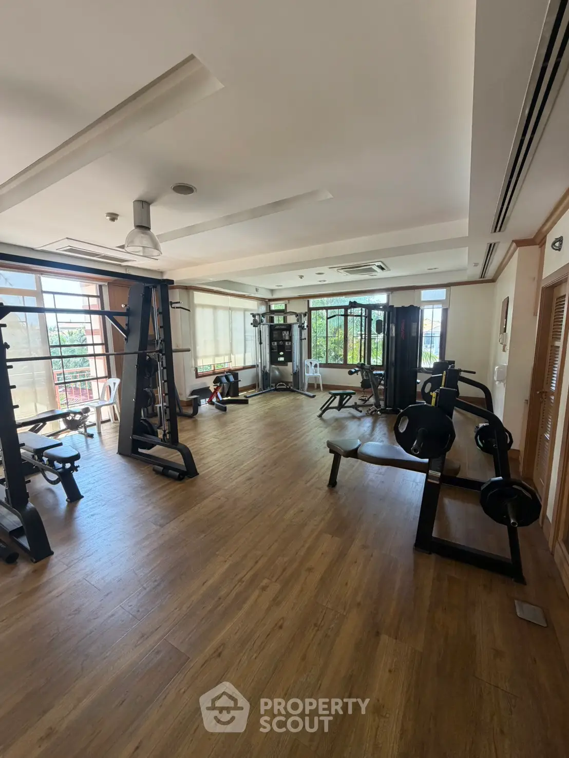 Spacious gym with modern equipment and large windows offering natural light