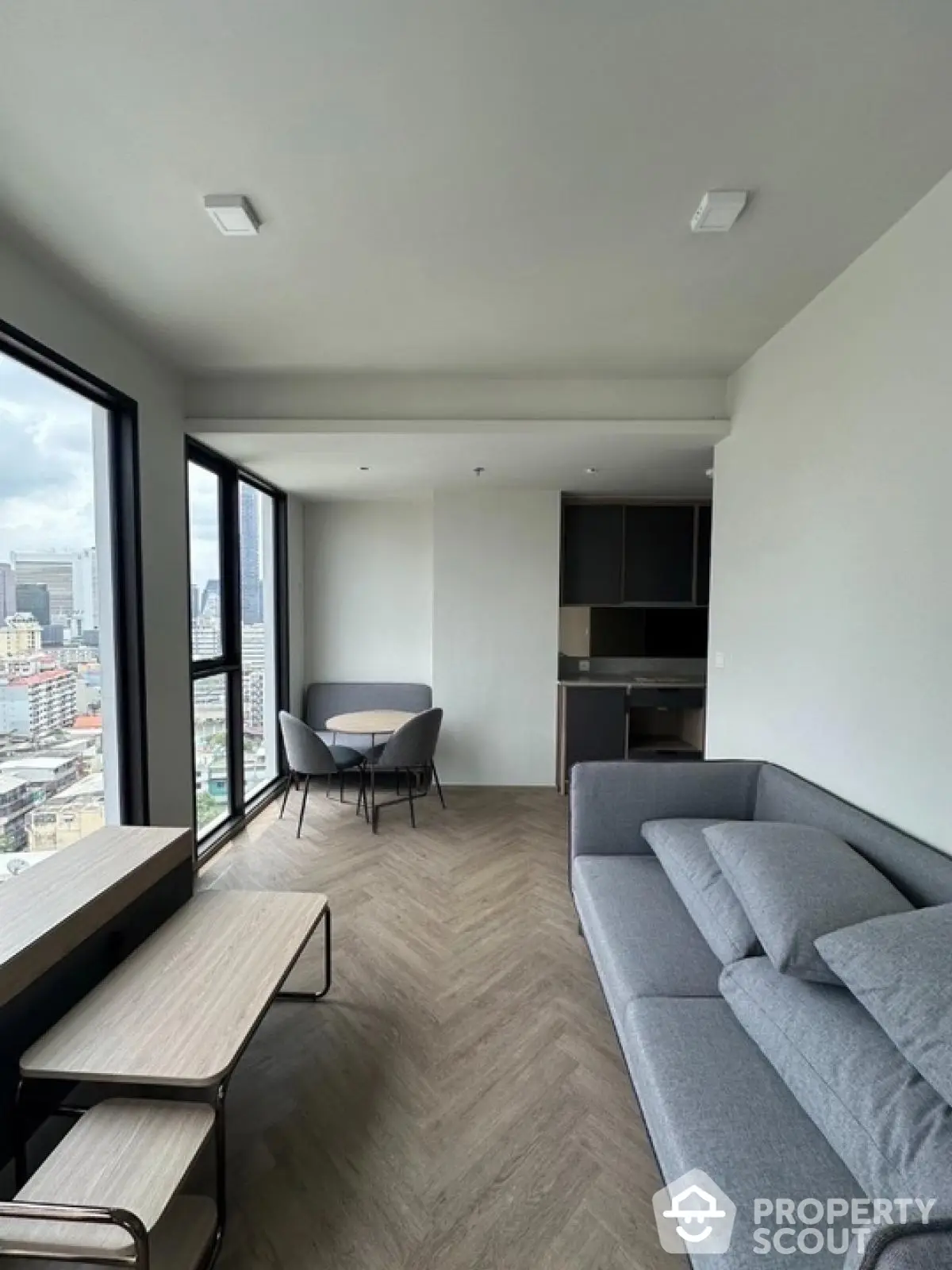 Modern living room with city view, sleek furniture, and open layout in high-rise apartment.