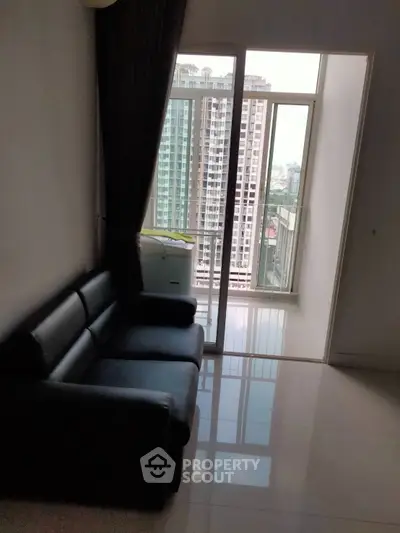 Modern living room with sleek black sofa and large window offering city view