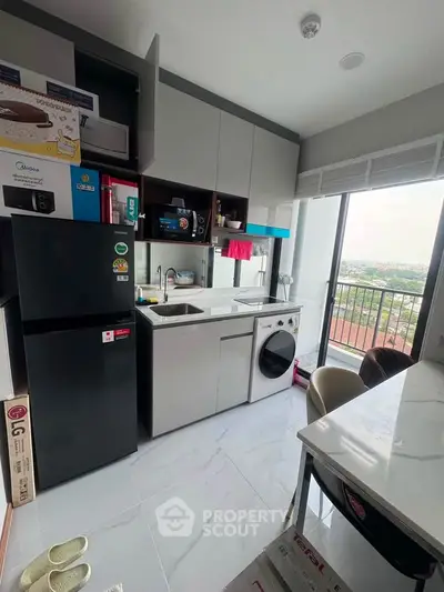 Modern kitchen with sleek appliances and city view, featuring a washing machine and ample storage.