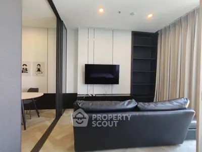 Modern living room with sleek black sofa, wall-mounted TV, and elegant decor