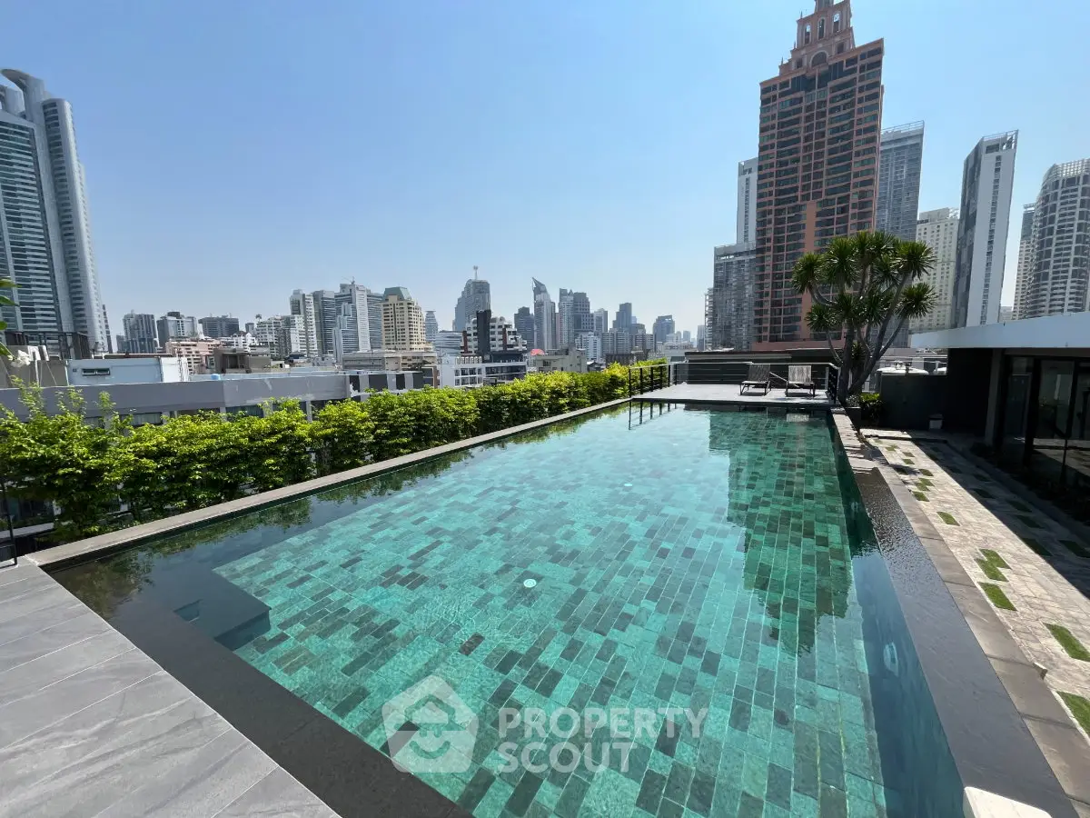 Luxurious rooftop pool with stunning city skyline views in a modern high-rise building.