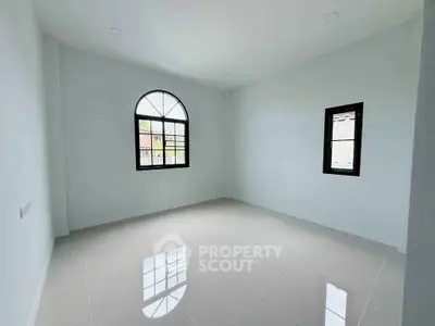 Spacious empty room with glossy tiled floor and arched window, perfect for customization.