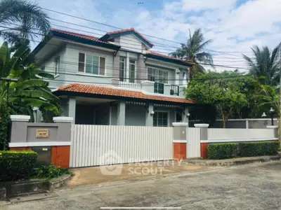 Charming two-story house with lush greenery and spacious driveway in a serene neighborhood.