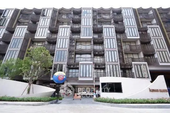 Modern multi-story residential building with unique architectural design and landscaped entrance.