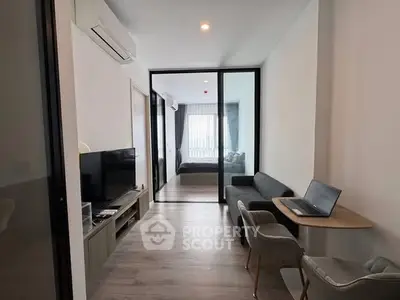Modern apartment interior with living room and bedroom, featuring sleek furniture and natural light.