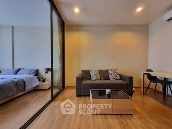 Modern living room with cozy sofa and glass partition to bedroom