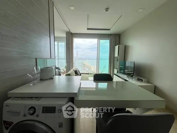 Modern living room with ocean view, featuring a washing machine and sleek furniture.