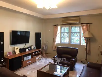 Cozy living room with leather sofas, TV, and natural light from window.