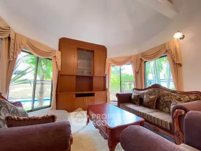Elegant living room with classic furniture and large windows overlooking greenery.