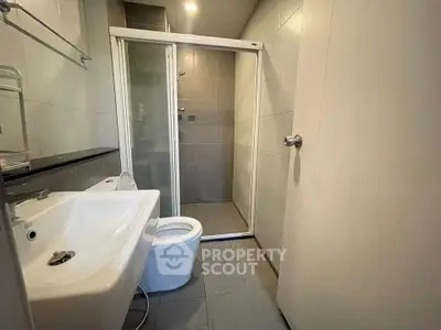 Modern bathroom with sleek fixtures and glass shower enclosure in contemporary apartment.