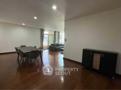 Spacious open-plan living and dining area with modern furniture and wooden flooring.
