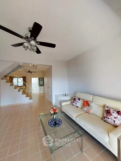 Spacious living room with modern decor and ceiling fan in a bright, airy home.