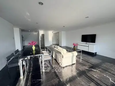 Spacious modern living room with sleek black flooring, elegant dining area, and large TV setup.