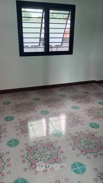 Spacious room with decorative tiled flooring and large window, ideal for customization.