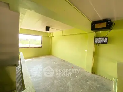 Spacious room with large window and green walls, ideal for customization.