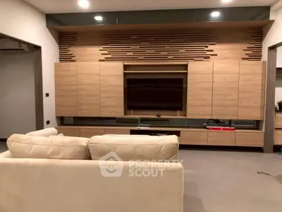 Modern living room with stylish wooden wall unit and cozy beige sofa.
