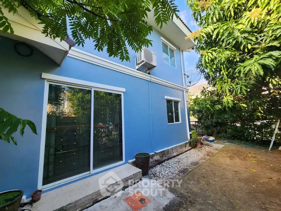 Charming blue two-story house with lush garden and sliding glass doors