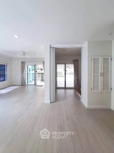 Spacious open-plan living area with large windows and light wood flooring.