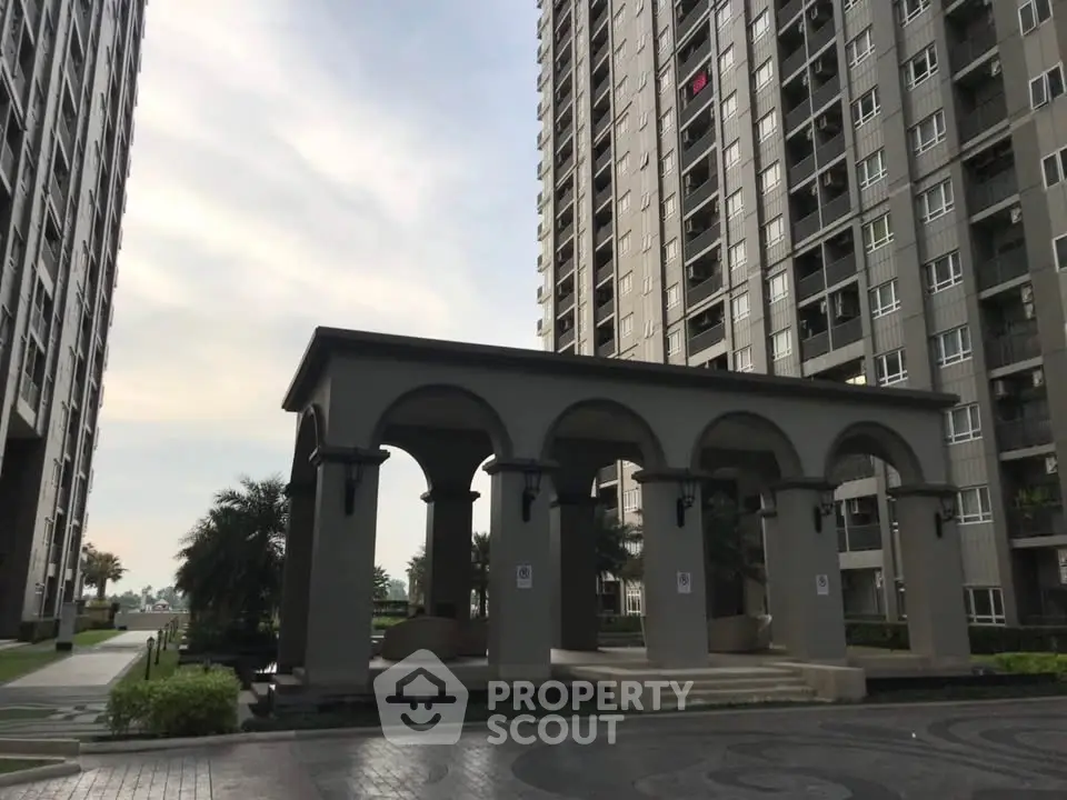 Modern high-rise apartment buildings with elegant outdoor pavilion and landscaped surroundings.