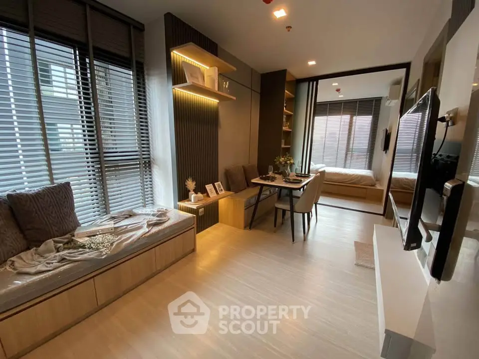 Modern open-plan living room with dining area and cozy bedroom in stylish apartment.