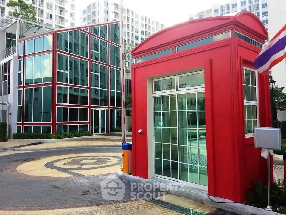 Modern apartment complex with unique red architectural feature and glass facade.