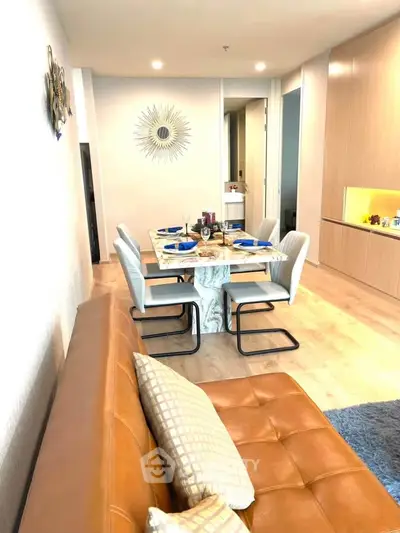 Modern living room with stylish dining area and leather sofa, featuring elegant decor and warm lighting.