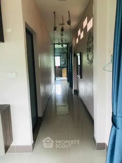 Bright hallway with modern decor leading to a distant room, featuring wall clock and hanging plants.