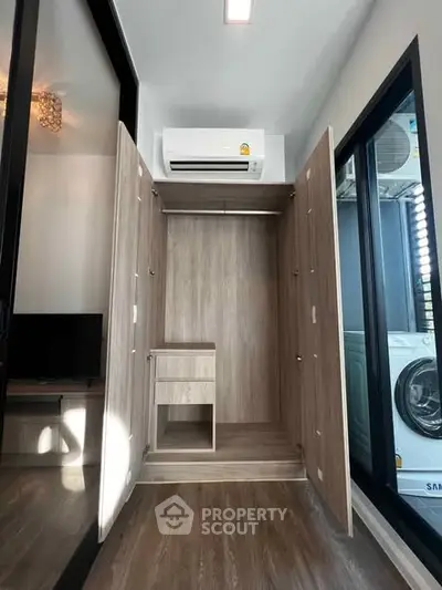 Modern apartment with built-in wardrobe and air conditioning, featuring a sleek washing machine.