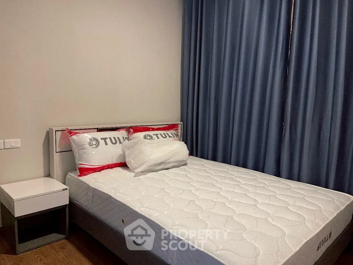 Cozy bedroom with modern bed and side table, featuring elegant blue curtains.