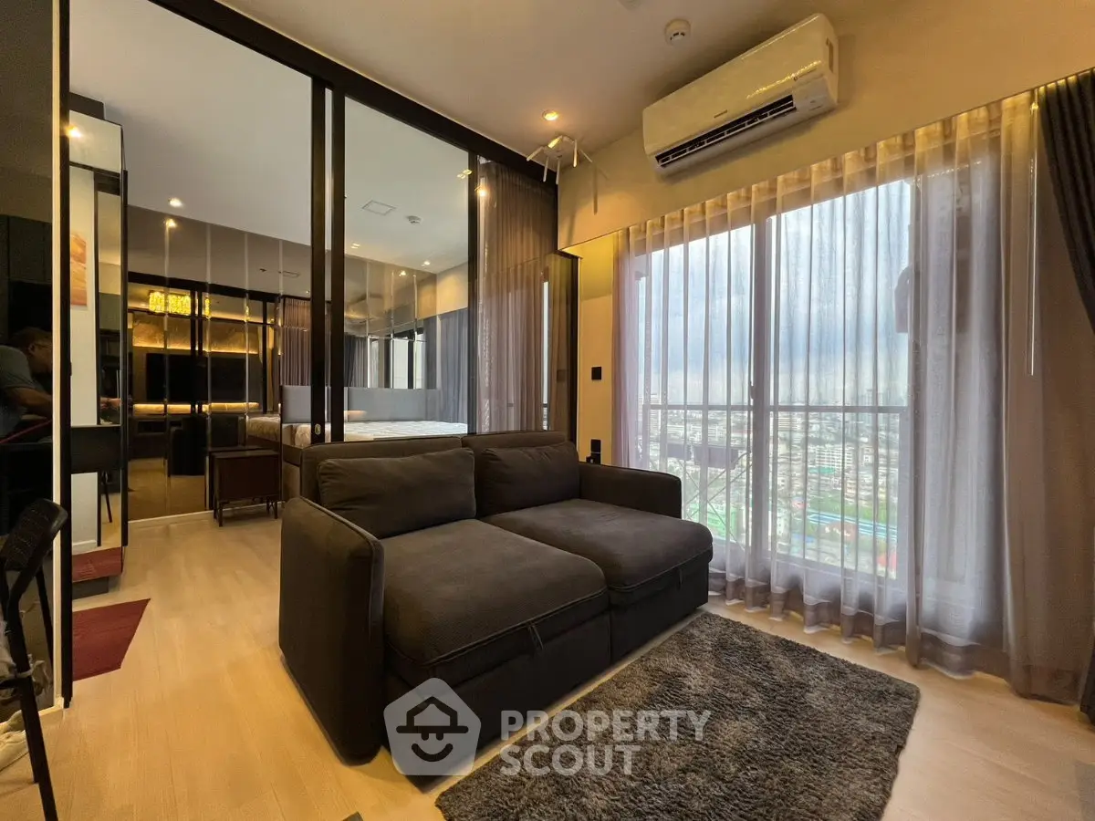 Modern living room with large windows and city view, featuring a cozy sofa and stylish decor.