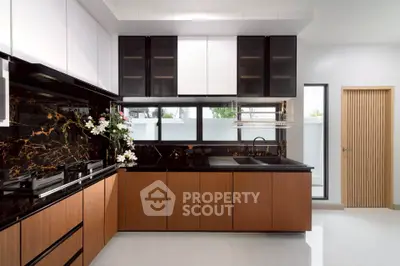 Modern kitchen with sleek black and wood cabinetry, featuring a stylish open layout and elegant marble accents.